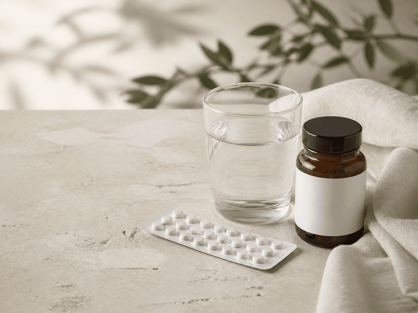 Unbranded contraceptive blister pack, water and supplement jar on a neutral tabletop